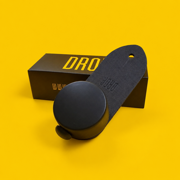 DROP guitar strap adjuster and package on a yellow background
