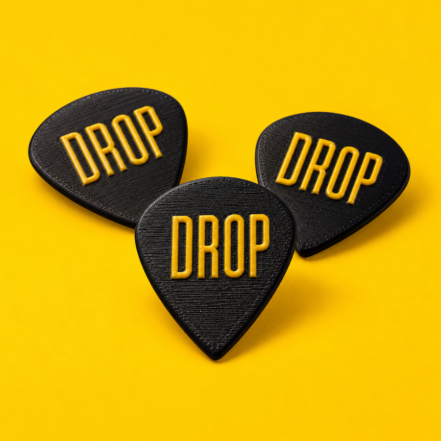 Three black DROP guitar picks with yellow logos on a yellow background